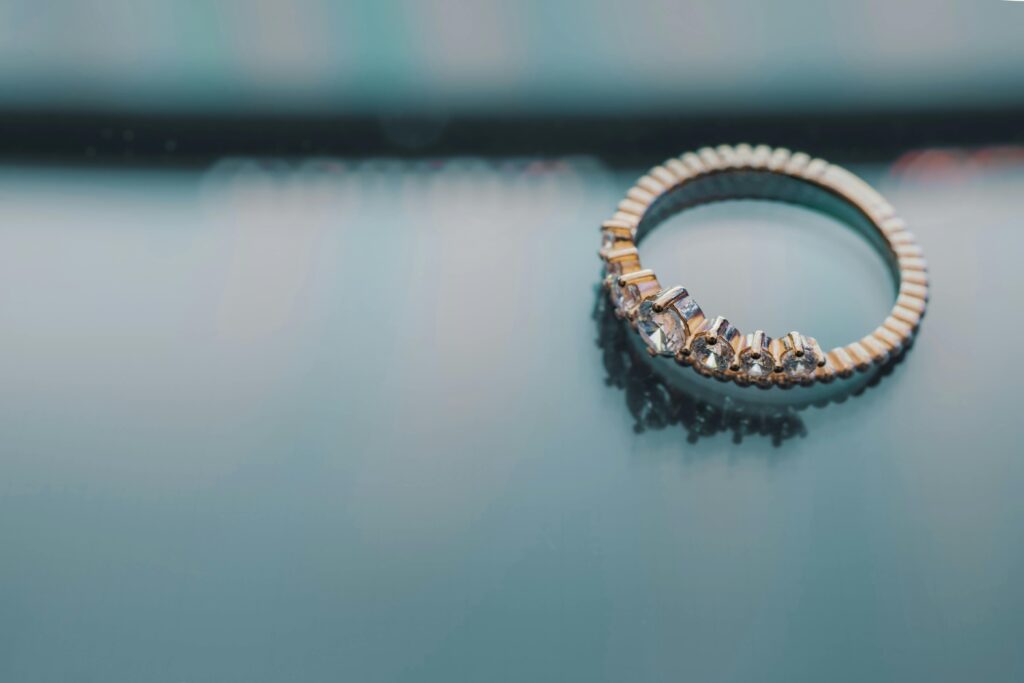 Close-up of a gold ring with diamonds on a reflective surface, showcasing elegance and luxury.